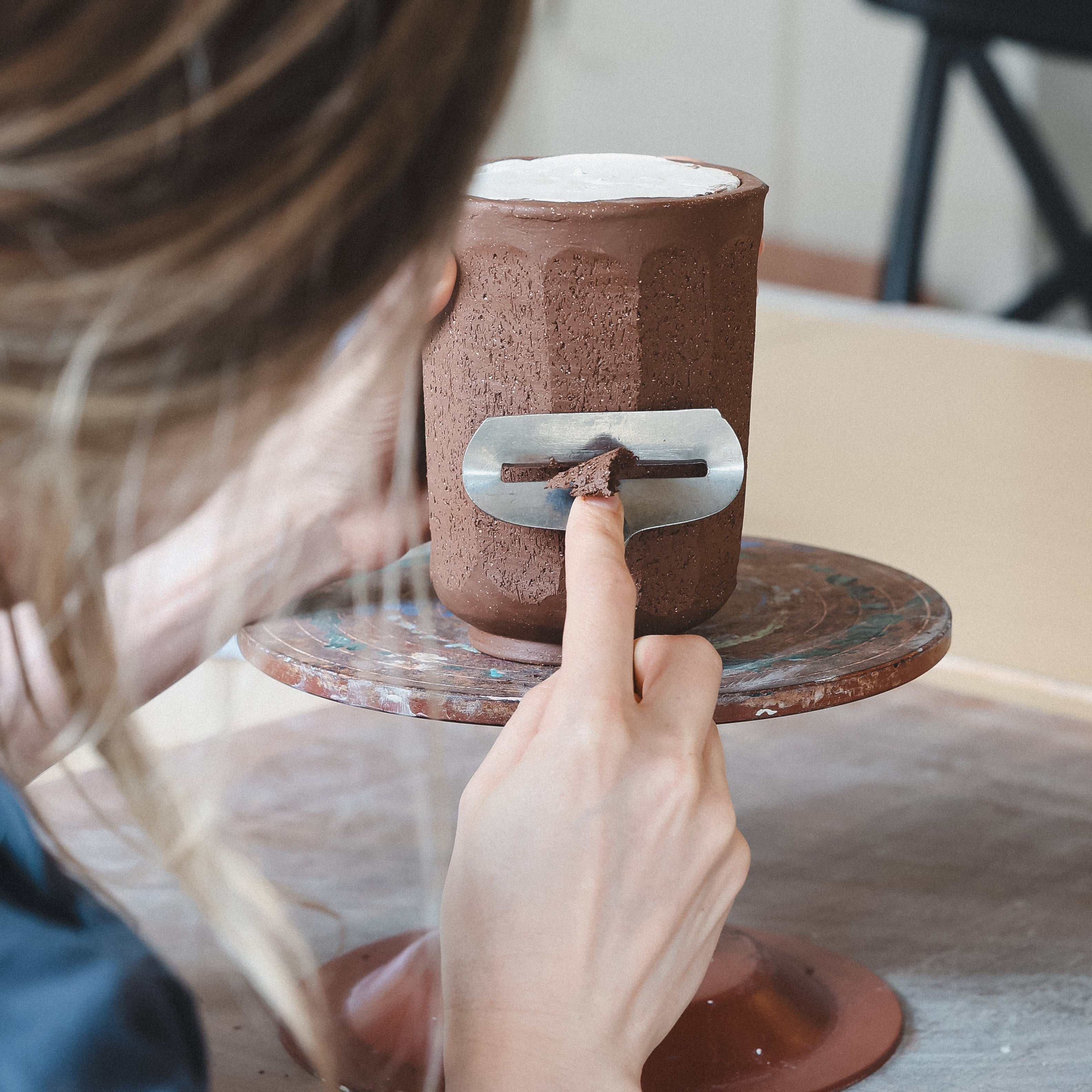 Person using a tool on a ceramic mug